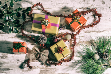 Photo of Christmas still life with gifts and with analog - retro effect. Christmas presents create still life. View from above. Gifts, colorful packages, pine cones and needles on an old oak table.