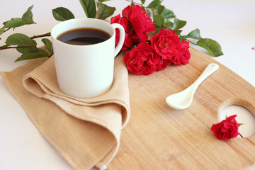 Hot coffe in awhite cup with natural red roses
