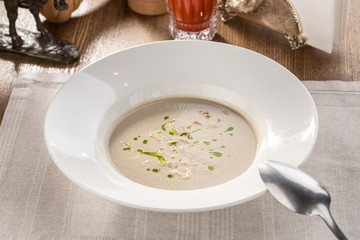 champignon cream soup in white bowl with tomato juice on fabric napkin on the table
