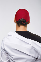 Cropped back view shot of a dark-haired man, wearing red baseball cap with lettering 