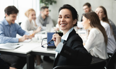 Female top manager smiling to camera at meeting - obrazy, fototapety, plakaty