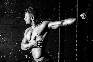 Young sweaty muscular strong fit man stretching his arm and chest muscles after heavy and hard...