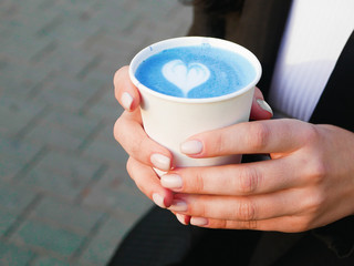 Matcha blue tea in the hands. Matcha blue tea. Side view of matcha blue tea. Drink on the spot. With a heart-shaped pattern. Love for the match. latte matcha. Blue latte art