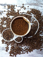 close-up of a coffee grinder with ground coffee on a wooden tabletop background with freshly roasted brown aromatic coffee beans