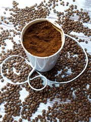 close-up of a coffee grinder with ground coffee on a wooden tabletop background with freshly roasted brown aromatic coffee beans