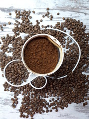 close-up of a coffee grinder with ground coffee on a wooden tabletop background with freshly roasted brown aromatic coffee beans