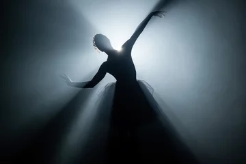  Solo-optreden door ballerina in tutu-jurk tegen de achtergrond van lichtgevende neonspots in theater. Silhouet van een vrouw in pointe-schoenen die klassieke bewegingen dansen. © kohanova1991