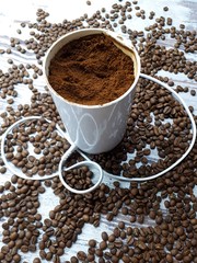 close-up of a coffee grinder with ground coffee on a wooden tabletop background with freshly roasted brown aromatic coffee beans