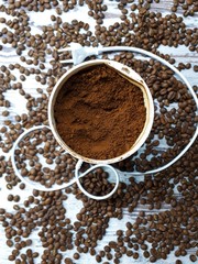 close-up of a coffee grinder with ground coffee on a wooden tabletop background with freshly roasted brown aromatic coffee beans