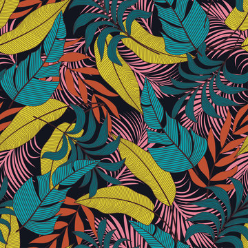 Original seamless tropical pattern with bright yellow and pink plants and leaves on a dark background. Seamless exotic pattern with tropical plants. Exotic wallpaper. Hawaiian style.