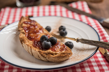 Healthy snack with toasted rustic bread with peanut butter, strawberry jam, cinnamon and blueberries. Horizontal. Selective focus. Closeup.