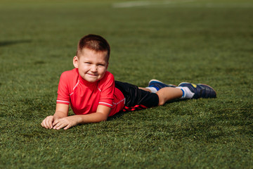Fototapeta na wymiar Boy in red T-shirt lies on green grass