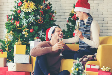 Merry Christmas. Young couple celebrating and party and drinking champagne new year and Christmas with gift and Christmas tree at home.