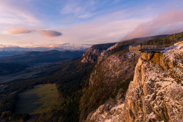 Fototapeta na wymiar Hiker is standing on a Mountain Peak watching the Sunrise in Winter