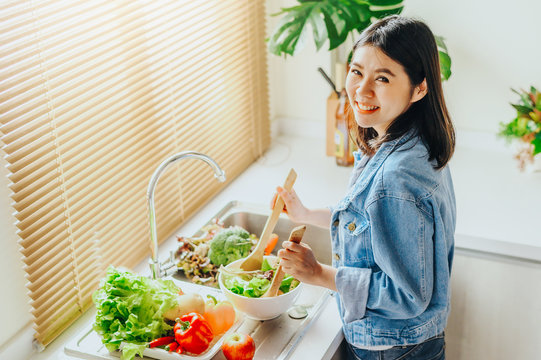 woman mixing salad in bowl while cooking at home