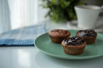 Muffin with chocolate cream next to the window with coffee