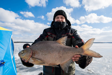man and woman holding a pike on the ice. winter fishing