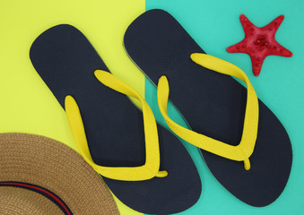 Tropical summer concept. black sandals, yellow straps and brown -brimmed hats from the top view on...
