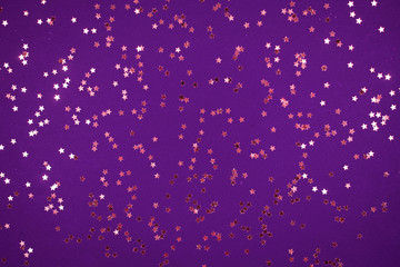 little gold stars on purple background Festive holiday background. Celebration concept. Top view,