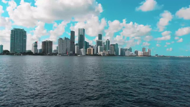 Drone flying towards Brickell skyline over water in Miami
