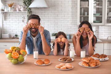happy family covering eyes with biscuits on the kitchen