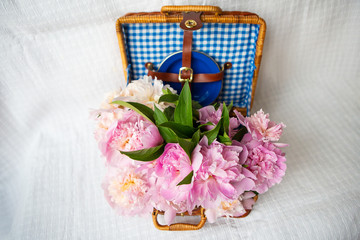Fototapeta na wymiar The beauty of a pink peonies bouquet in a vintage authentic brown suitcase.