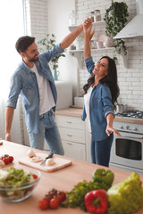 husband and wife dancing on the kitchen while preparing dinner