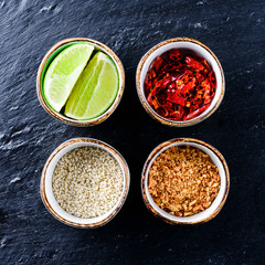 slices of lime and sesame seeds in a bowl on a black stone - spices in Korean cuisine