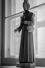 Plaster statue of a nun in front of a window