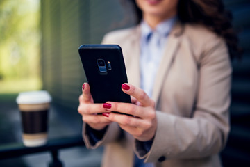 Woman in suit holding smartphone,selective focus on phone