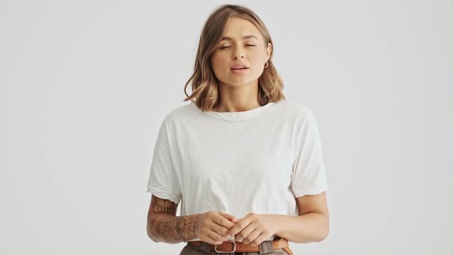 Beautiful young woman wearing a basic t-shirt listening to someone seriously then shaking her head negatively isolated over white background