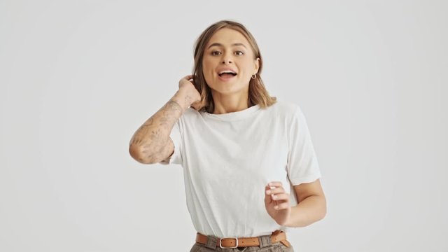 Smiling young woman wearing basic t-shirt running in then apologizing about her late isolated over white background