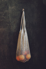 Reusable Mesh cottone Bags hanging on the wall in house. Eco friendly package for grocery with...