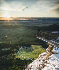 Hiker is standing on a Mountain Peak watching the Sunrise in Winter