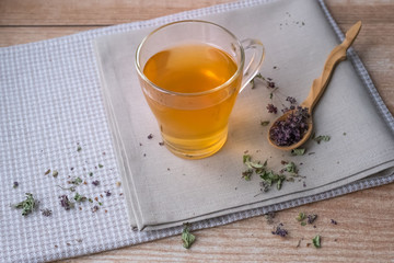 Warm oregano tea on beige linen napkins on the table.