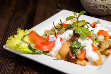 Plate with salad on a wooden background. Vegetable salad in a plate close-up.