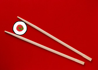 Wooden chopsticks on a red background. Sushi and wooden chopsticks. The concept of eating sushi.