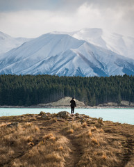 Junge Frau steht vor Lake Pukaki und macht ein Bild von einem Berg. Das Foto wurde im verschneiten...