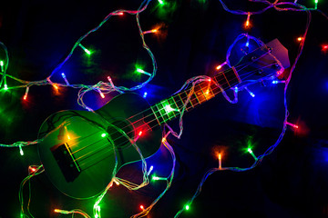 Colored lights of garlands and ukulele close-up. 