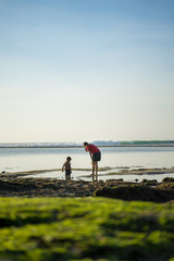 Ein kleiner Junge spielt mit seiner Mutter im Ozean am Jimbaran beach auf der Insel Bali