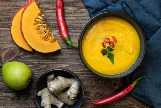 Zupa z dyni na ciemnym drewnianym tle.