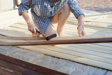 Home improvement - handywoman painting wooden plank outdoors