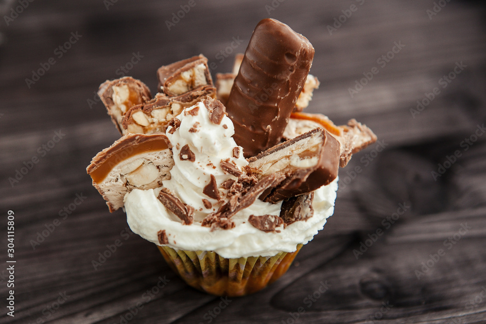 Wall mural  cupcake with white cream and chocolate with nuts on a dark background