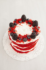 homemade red velvet cake decorated with berries on a light wooden background