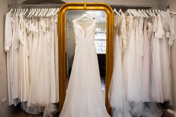 Wedding dresses hanging on a hanger. Fashion look. Interior of bridal salon.