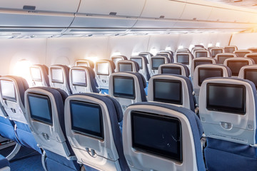 Economy class empty seats with entertainment system onboard a wide-body airliner.