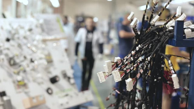 the worker tests for the definition of quality part of the wiring for cars at a modern plant in a production workshop