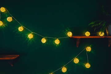 Yellow light bulbs on dark green wall. Holiday's decoration garland 