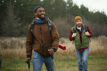 Group of friends on a camping or hiking trip in autumn day. Men and women with touristic backpacks...