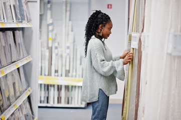 African woman choosing tulle in the bathroom for her apartment in a modern home furnishings store.